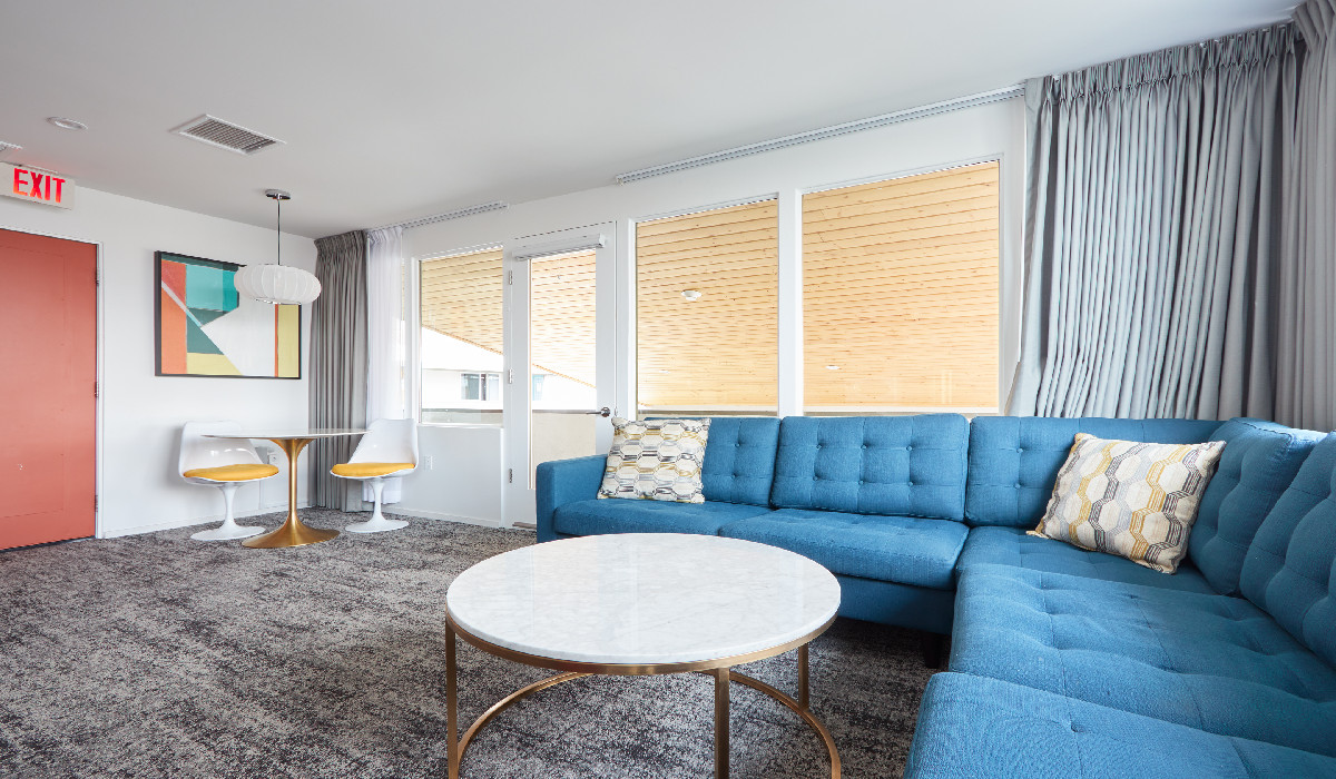 A living room with a blue couch, coffee table, and chairs.